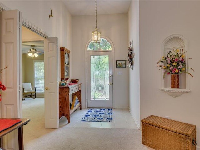 carpeted foyer with ceiling fan and a high ceiling