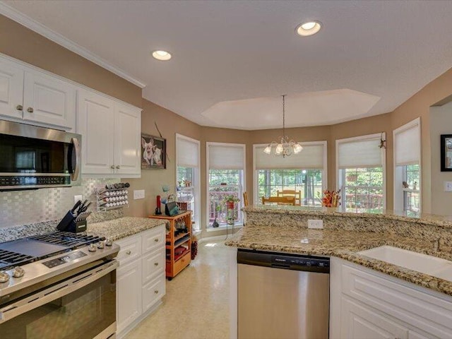 kitchen with white cabinetry, hanging light fixtures, an inviting chandelier, tasteful backsplash, and appliances with stainless steel finishes