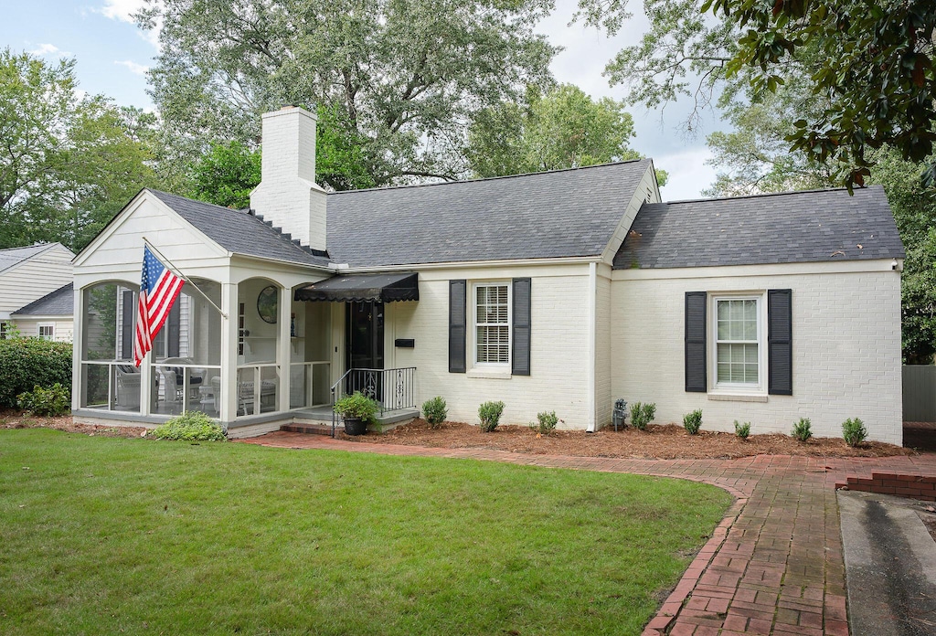 3117 Bransford Rd, Augusta, GA 30909 - ranch-style house with brick siding, a front lawn, a chimney, a sunroom, and a shingled roof