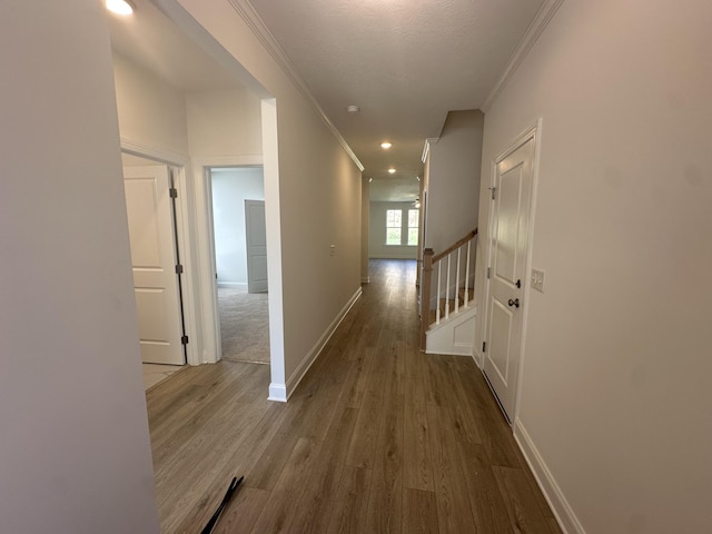 corridor with baseboards, wood finished floors, stairs, and crown molding