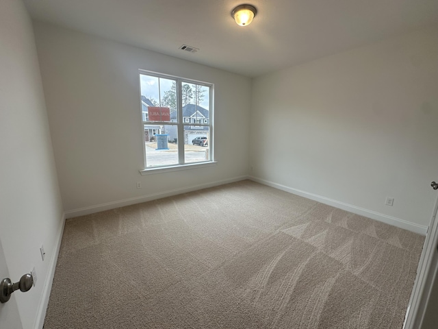 unfurnished room with light colored carpet, visible vents, and baseboards