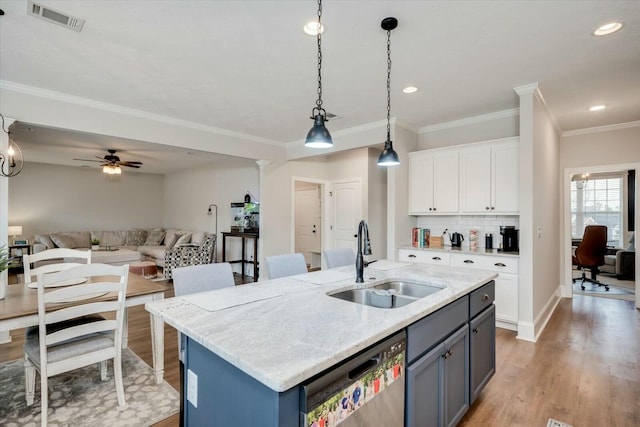 kitchen featuring white cabinetry, an island with sink, sink, stainless steel dishwasher, and light stone countertops