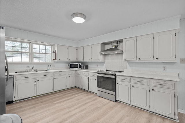 kitchen with stainless steel appliances, sink, wall chimney range hood, and light wood-type flooring