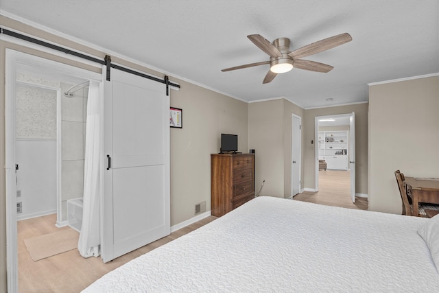 bedroom with crown molding, light hardwood / wood-style flooring, a barn door, and ceiling fan