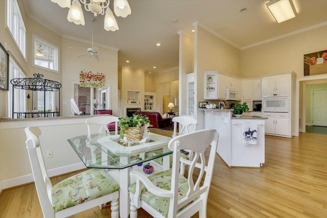 dining area with light hardwood / wood-style flooring, a high ceiling, and ornamental molding