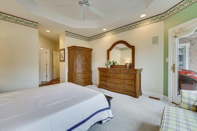 carpeted bedroom with a tray ceiling and ceiling fan