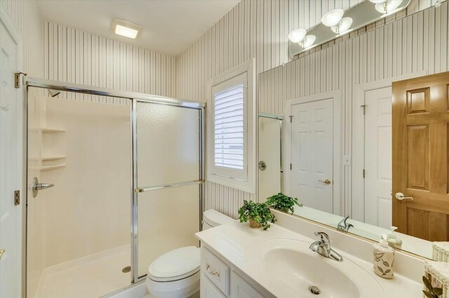 bathroom featuring vanity, toilet, and walk in shower