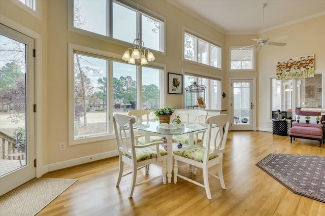 sunroom / solarium featuring ceiling fan with notable chandelier and plenty of natural light