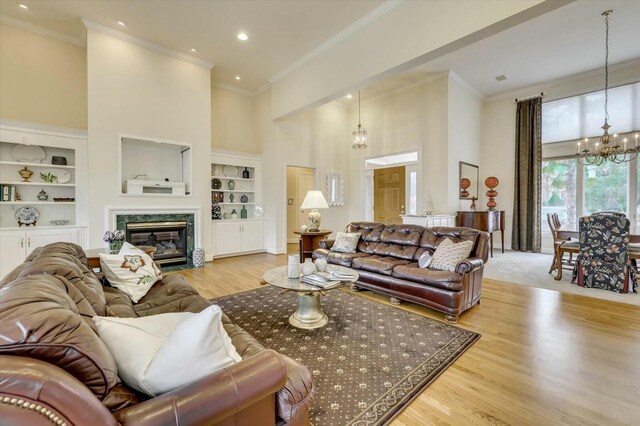 living room featuring a fireplace, a high ceiling, light wood-type flooring, and built in features