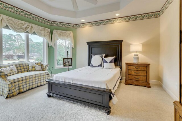 carpeted bedroom featuring a raised ceiling and ceiling fan