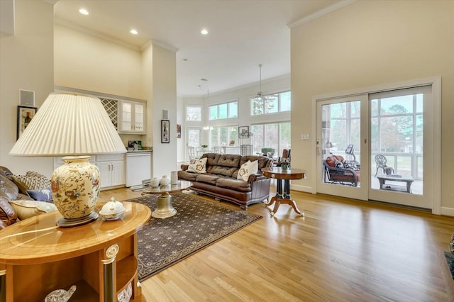 living room featuring a towering ceiling, light hardwood / wood-style floors, and a wealth of natural light