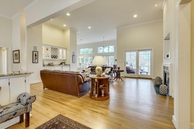 living room featuring light hardwood / wood-style flooring, a high ceiling, and ornamental molding