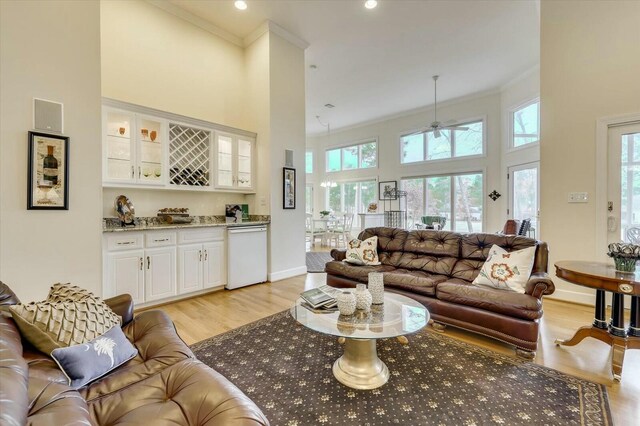 living room with a wealth of natural light, light hardwood / wood-style flooring, and crown molding