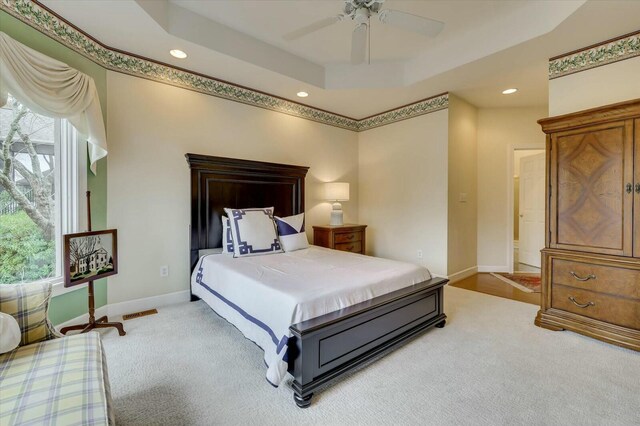 carpeted bedroom featuring ceiling fan and a tray ceiling