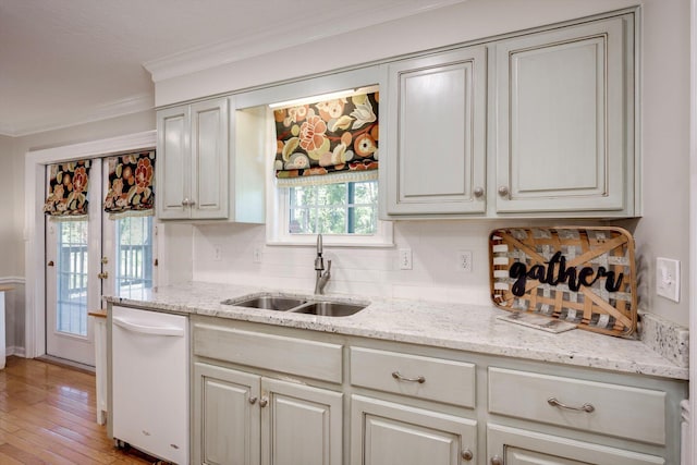 kitchen featuring dishwasher, a sink, crown molding, decorative backsplash, and light wood finished floors
