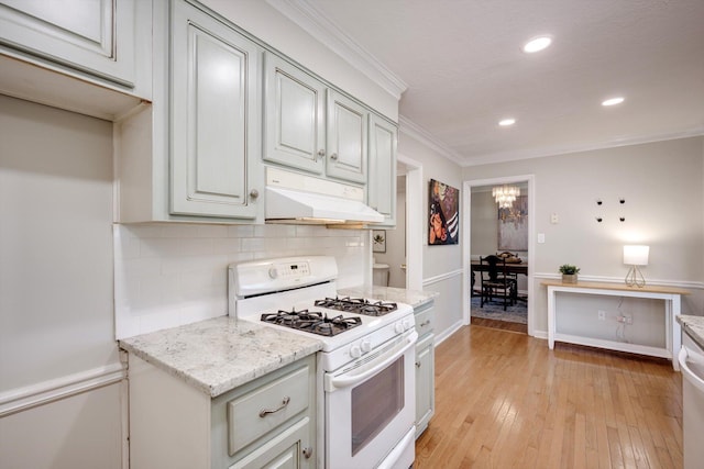 kitchen with gas range gas stove, under cabinet range hood, crown molding, tasteful backsplash, and light wood finished floors