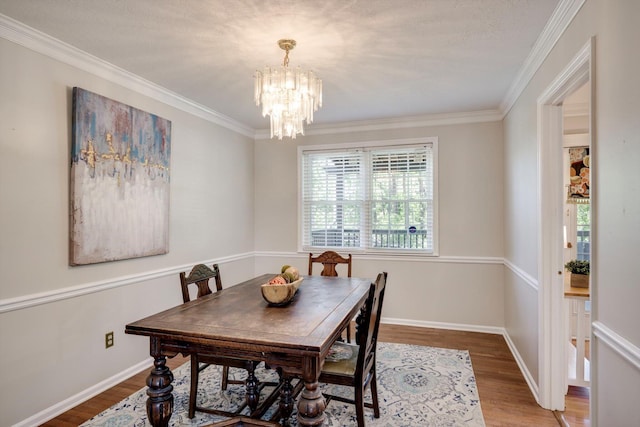 dining room featuring a chandelier, wood finished floors, ornamental molding, and baseboards