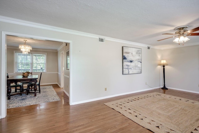 unfurnished room with wood finished floors, a chandelier, ornamental molding, baseboards, and ceiling fan