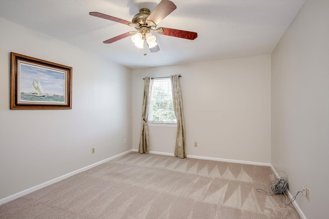 unfurnished room with light colored carpet, a ceiling fan, and baseboards