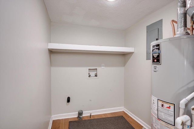 washroom with water heater, wood finished floors, baseboards, a textured ceiling, and washer hookup