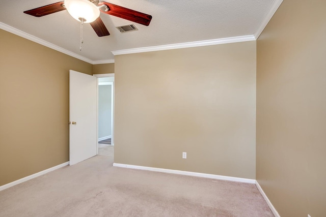 empty room featuring crown molding, light colored carpet, a ceiling fan, and baseboards