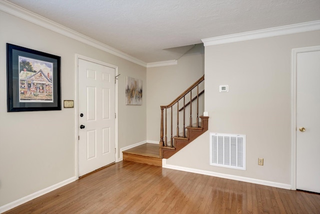 entryway featuring crown molding, wood finished floors, baseboards, and stairway