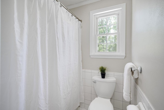 bathroom featuring wainscoting, toilet, tile walls, and a shower with curtain
