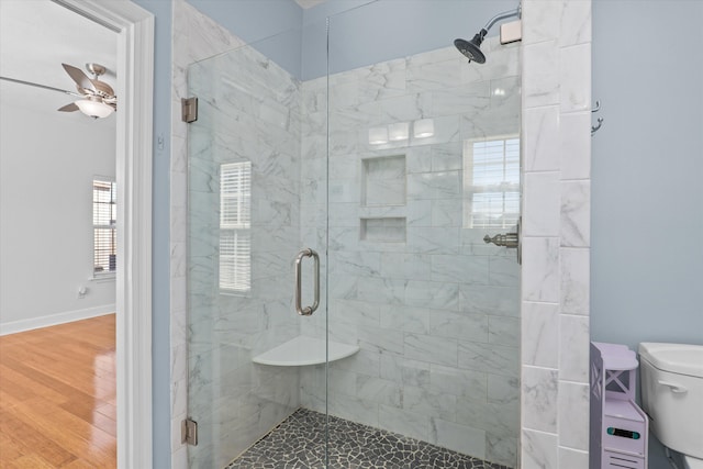 bathroom featuring hardwood / wood-style flooring, ceiling fan, toilet, and a shower with door