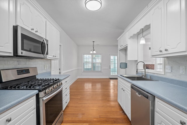 kitchen with sink, white cabinetry, stainless steel appliances, light hardwood / wood-style floors, and decorative light fixtures