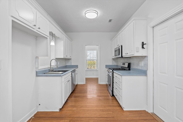 kitchen featuring sink, white cabinetry, tasteful backsplash, light wood-type flooring, and stainless steel appliances