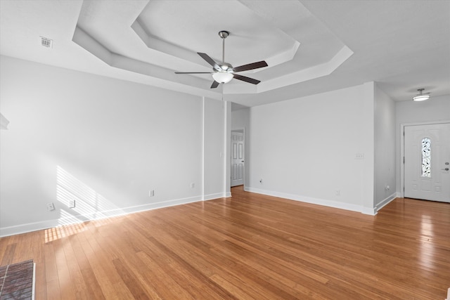 interior space featuring hardwood / wood-style floors, a tray ceiling, and ceiling fan