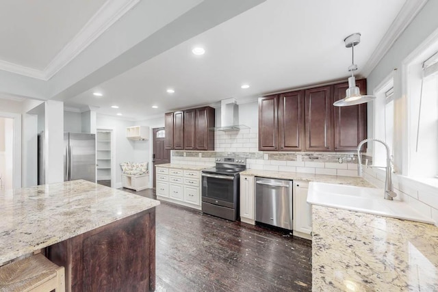 kitchen with wall chimney exhaust hood, sink, ornamental molding, appliances with stainless steel finishes, and pendant lighting