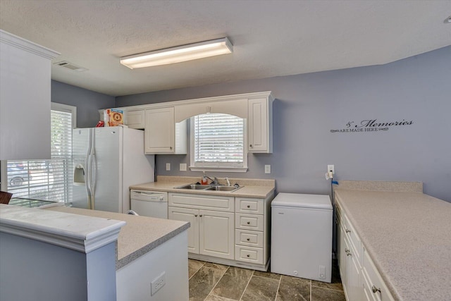 kitchen with a textured ceiling, white appliances, white cabinetry, and sink