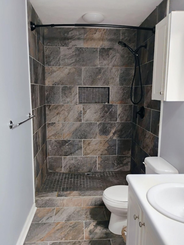 bathroom with vanity, toilet, and a tile shower