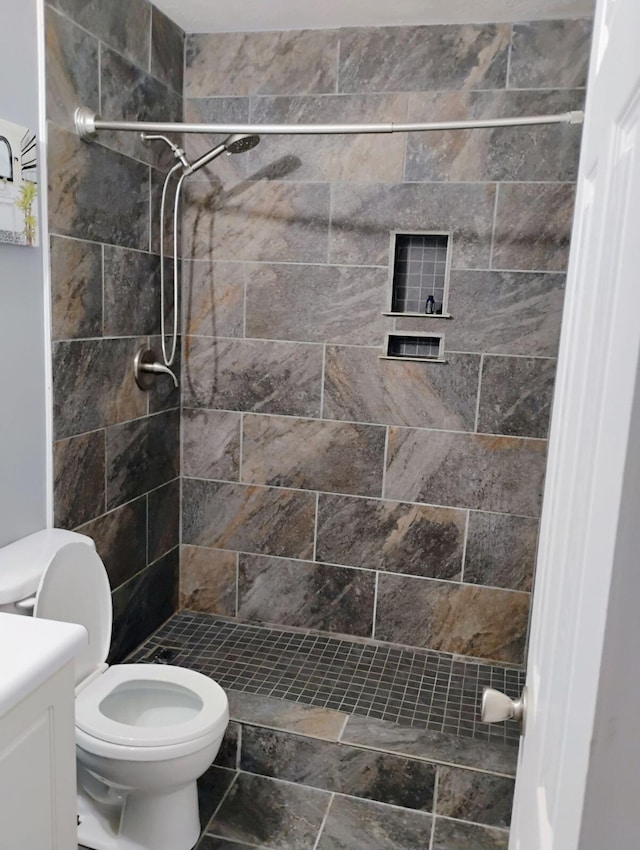 bathroom featuring vanity, toilet, and tiled shower