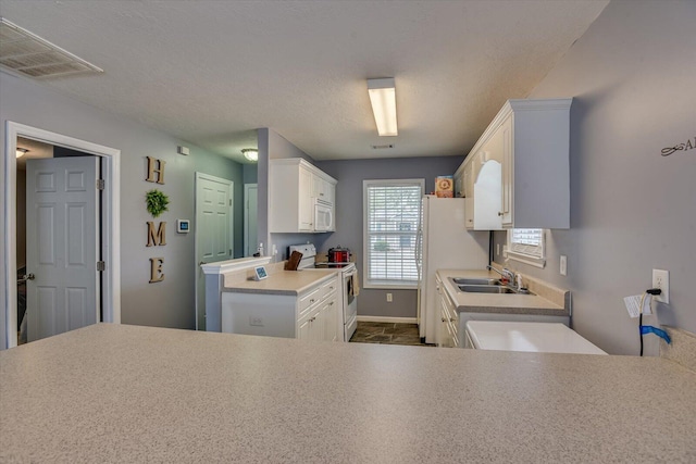 kitchen with white cabinets, white appliances, sink, and a textured ceiling