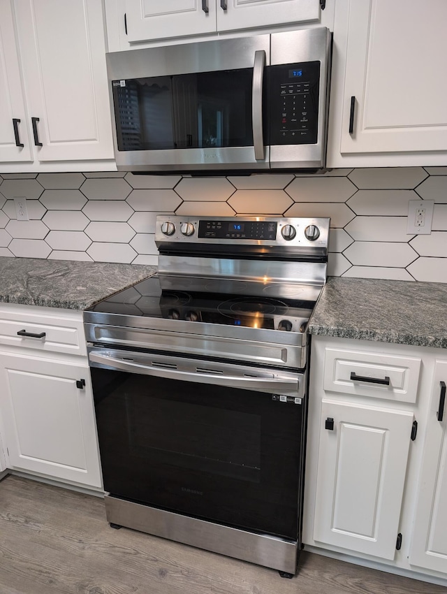 4331 Big Dipper Cir, Hephzibah, GA 30815 - kitchen with appliances with stainless steel finishes, tasteful backsplash, white cabinets, light wood-style flooring, and dark stone counters