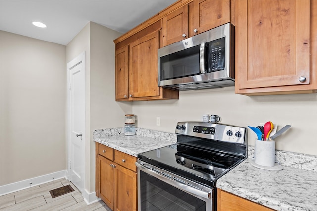 1216 Heard Ave, Augusta, GA 30904 - kitchen with appliances with stainless steel finishes, brown cabinetry, and light stone countertops