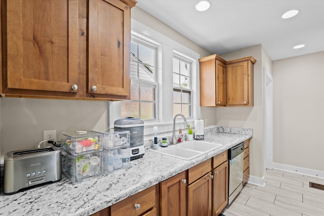 1216 Heard Ave, Augusta, GA 30904 - kitchen with brown cabinets, stainless steel dishwasher, recessed lighting, light stone counters, and light wood-style flooring