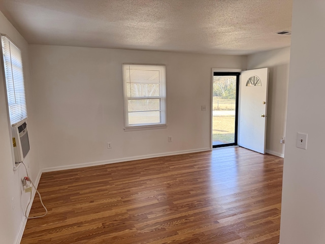 spare room featuring a textured ceiling, dark hardwood / wood-style floors, and cooling unit