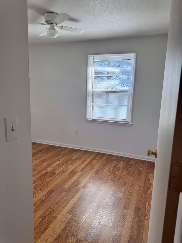 empty room with ceiling fan, a textured ceiling, and hardwood / wood-style flooring