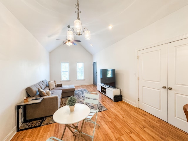 living room featuring ceiling fan with notable chandelier, light hardwood / wood-style floors, and lofted ceiling