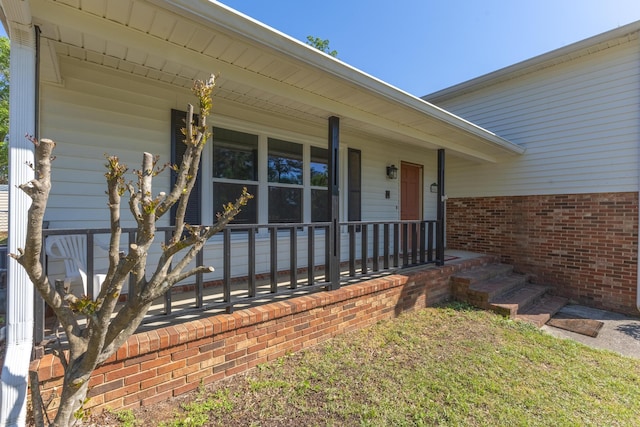 view of exterior entry featuring covered porch and brick siding