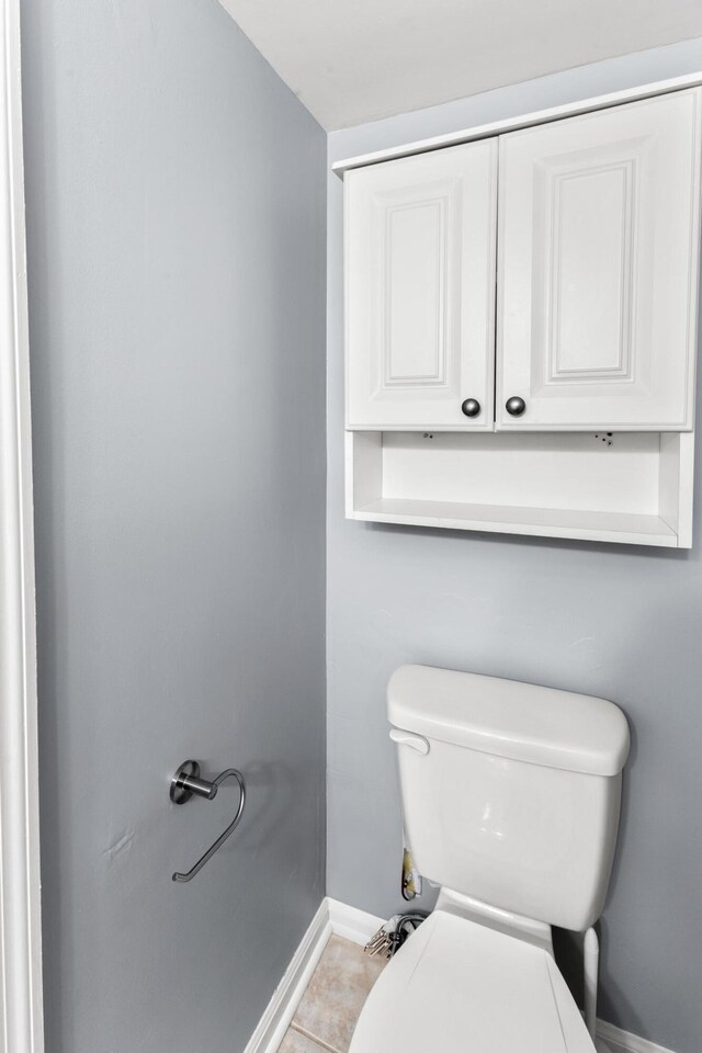 bathroom with tile patterned flooring, baseboards, and toilet