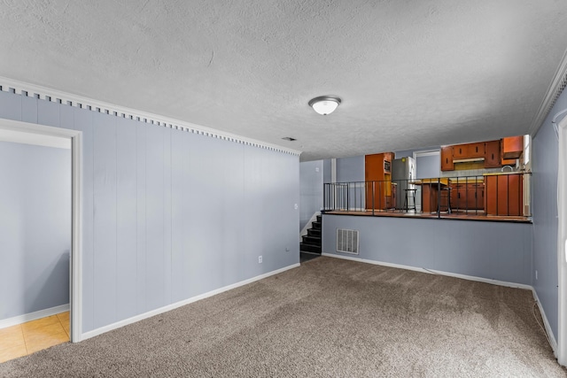 unfurnished living room with carpet, a textured ceiling, visible vents, stairway, and baseboards