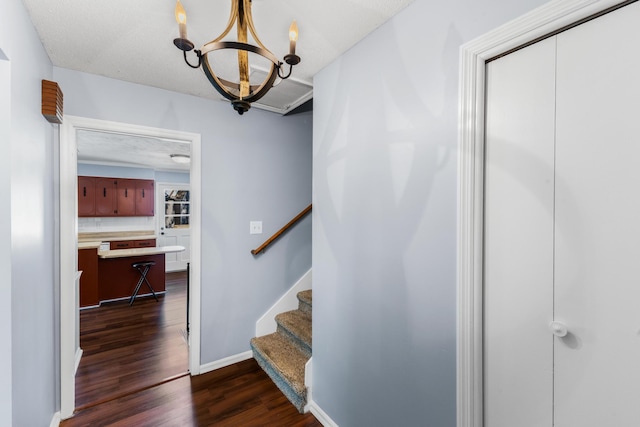 staircase with baseboards, a chandelier, and wood finished floors