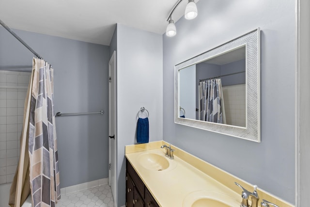 bathroom featuring curtained shower, double vanity, a sink, and tile patterned floors