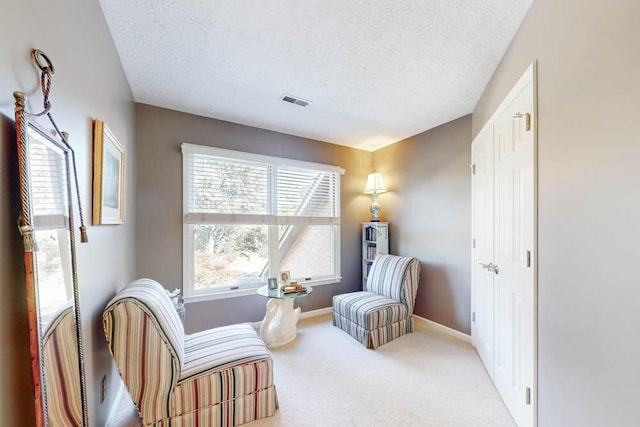 sitting room featuring carpet flooring and a textured ceiling