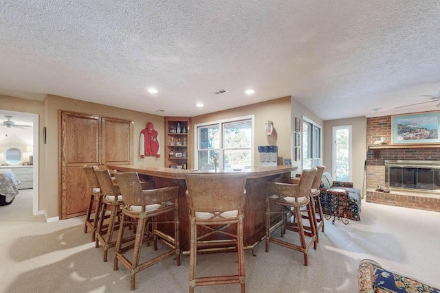 bar with ceiling fan, light carpet, and a fireplace