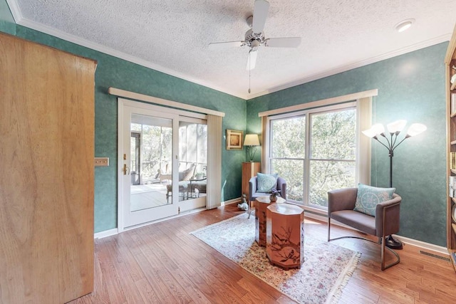 living area with ornamental molding, ceiling fan, and light hardwood / wood-style floors